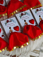 Red satin hats with gold trim and red heart-shaped decorations on a white surface.
