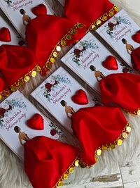 Valentine's Day-themed products with red satin ribbons and heart decorations on a textured surface.