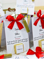 Gift boxes with red bows and personalized text on a table.