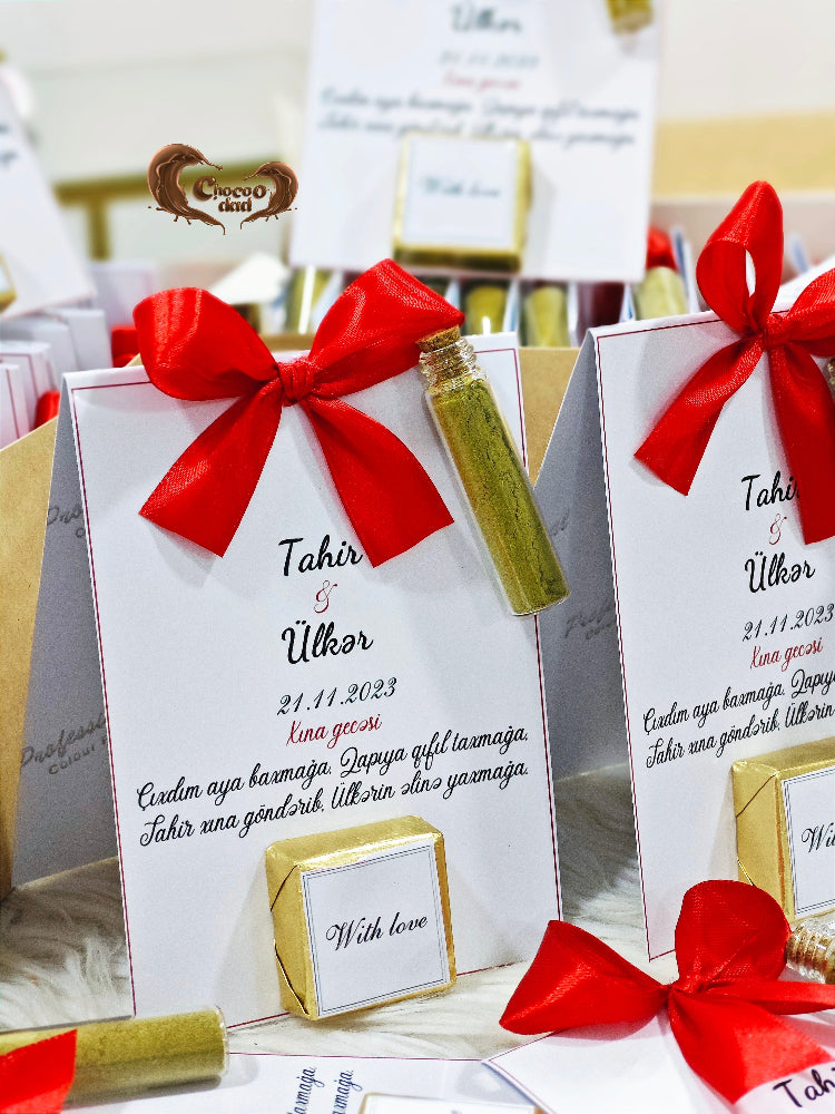 Gift boxes with red bows and personalized text on a table.