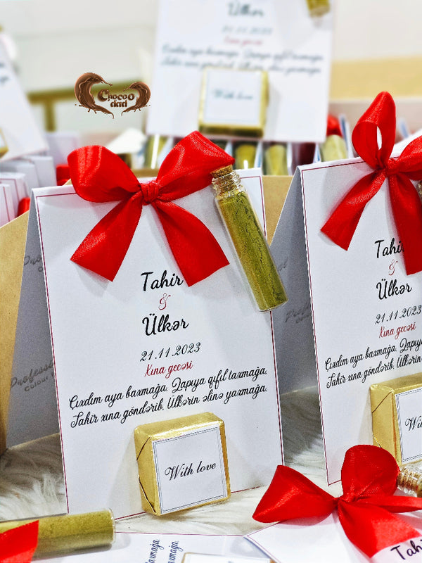 Gift boxes with red bows and personalized text on a table.