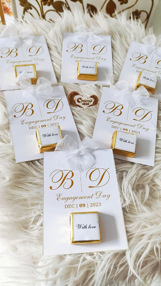 Personalized gift boxes with 'B D Engagement Day' text on a textured white surface.