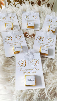 Personalized gift boxes with 'B D Engagement Day' text on a textured white surface.