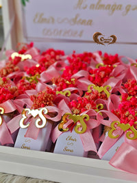 Decorative items with pink ribbons and red flowers on a white surface.