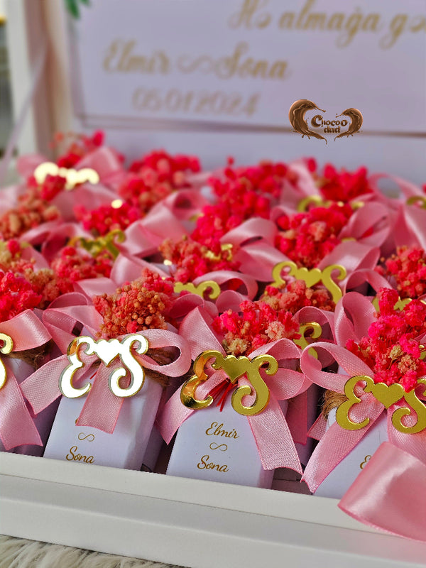Decorative items with pink ribbons and red flowers on a white surface.