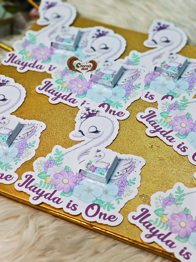 Sticker sheet with swan design and text 'Ilayda is One' on a gold background.