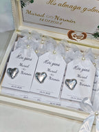 Heart-shaped silver charms on white cards with personalized text in a decorative box.