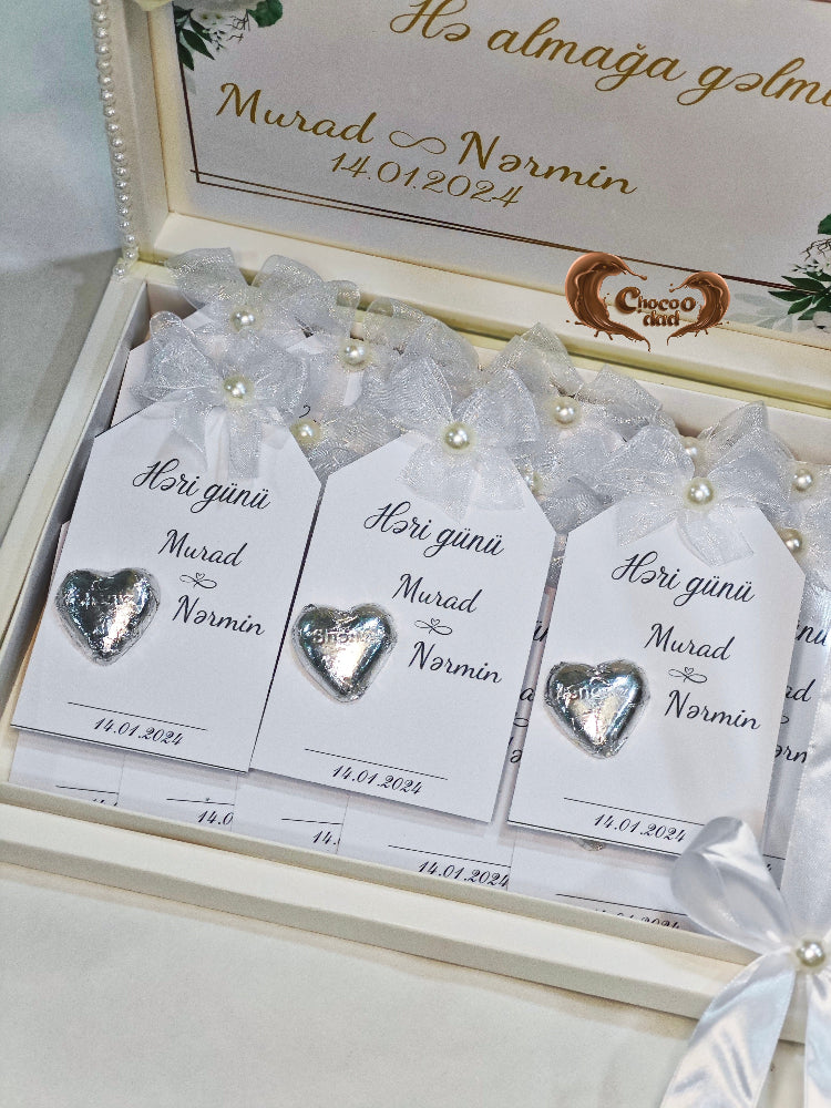 Heart-shaped silver charms on white cards with personalized text in a decorative box.