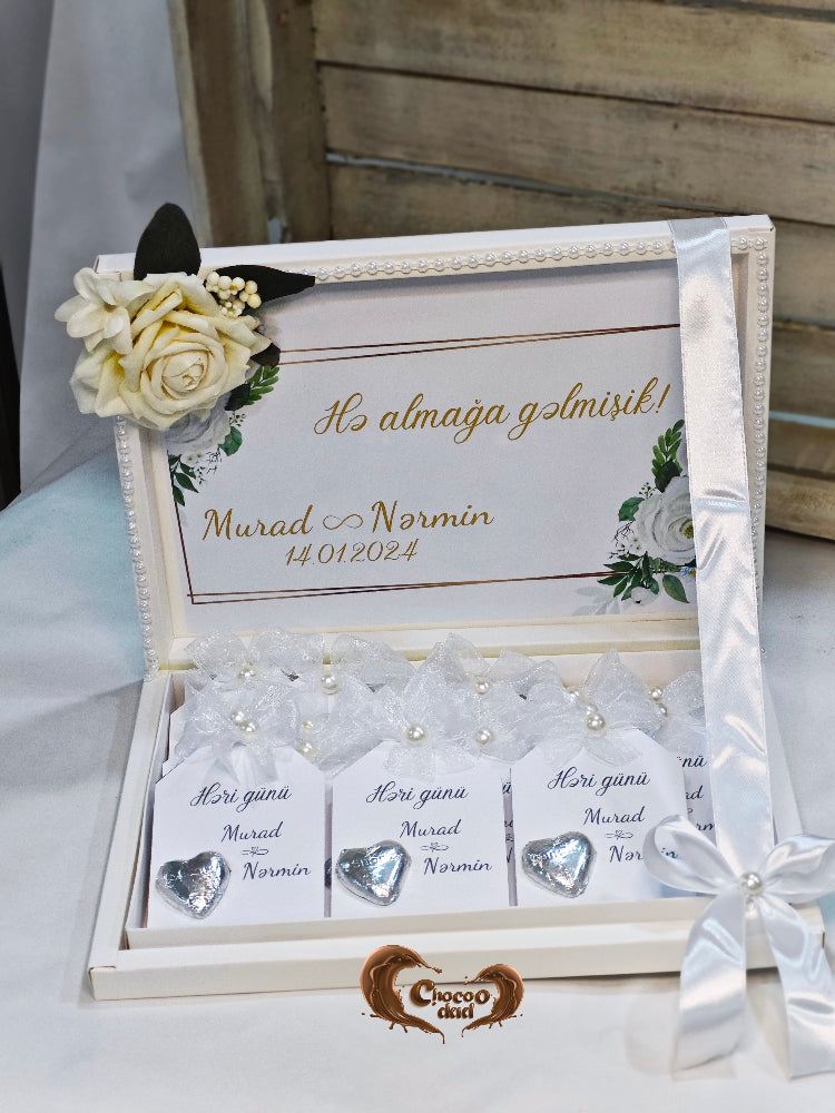 Decorative box with heart-shaped items and a floral arrangement on a white surface.