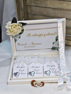 Decorative box with heart-shaped items and a floral arrangement on a white surface.