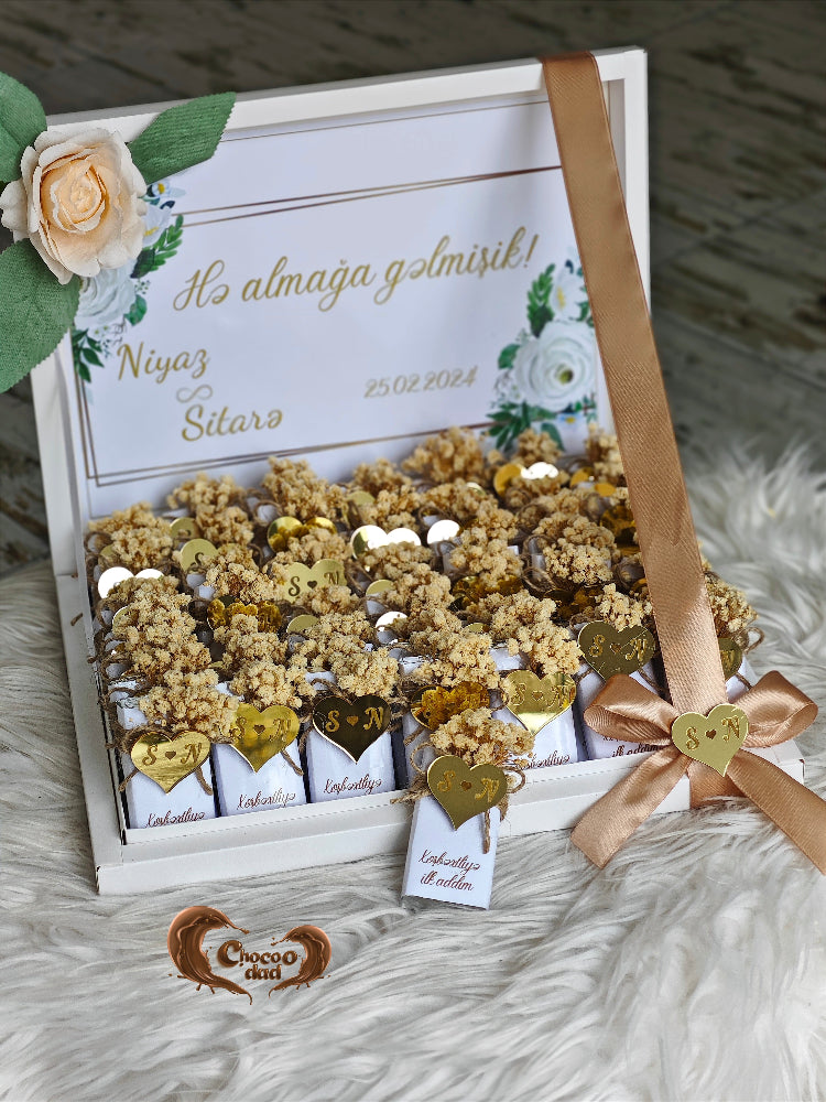 Gift box with decorative items and a ribbon on a textured surface