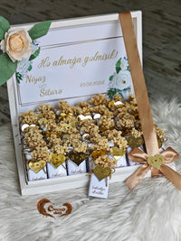 Gift box with decorative items and a ribbon on a textured surface