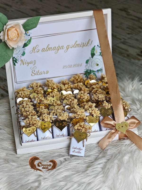 Gift box with decorative items and a ribbon on a textured surface