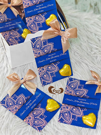 Blue birthday party invitations with gold heart-shaped candies on a white surface