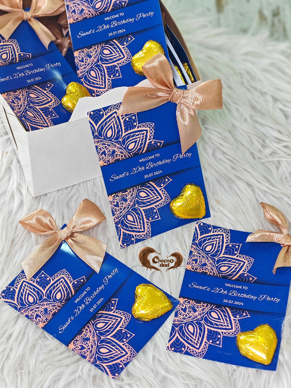 Blue birthday party invitations with gold heart-shaped candies on a white surface
